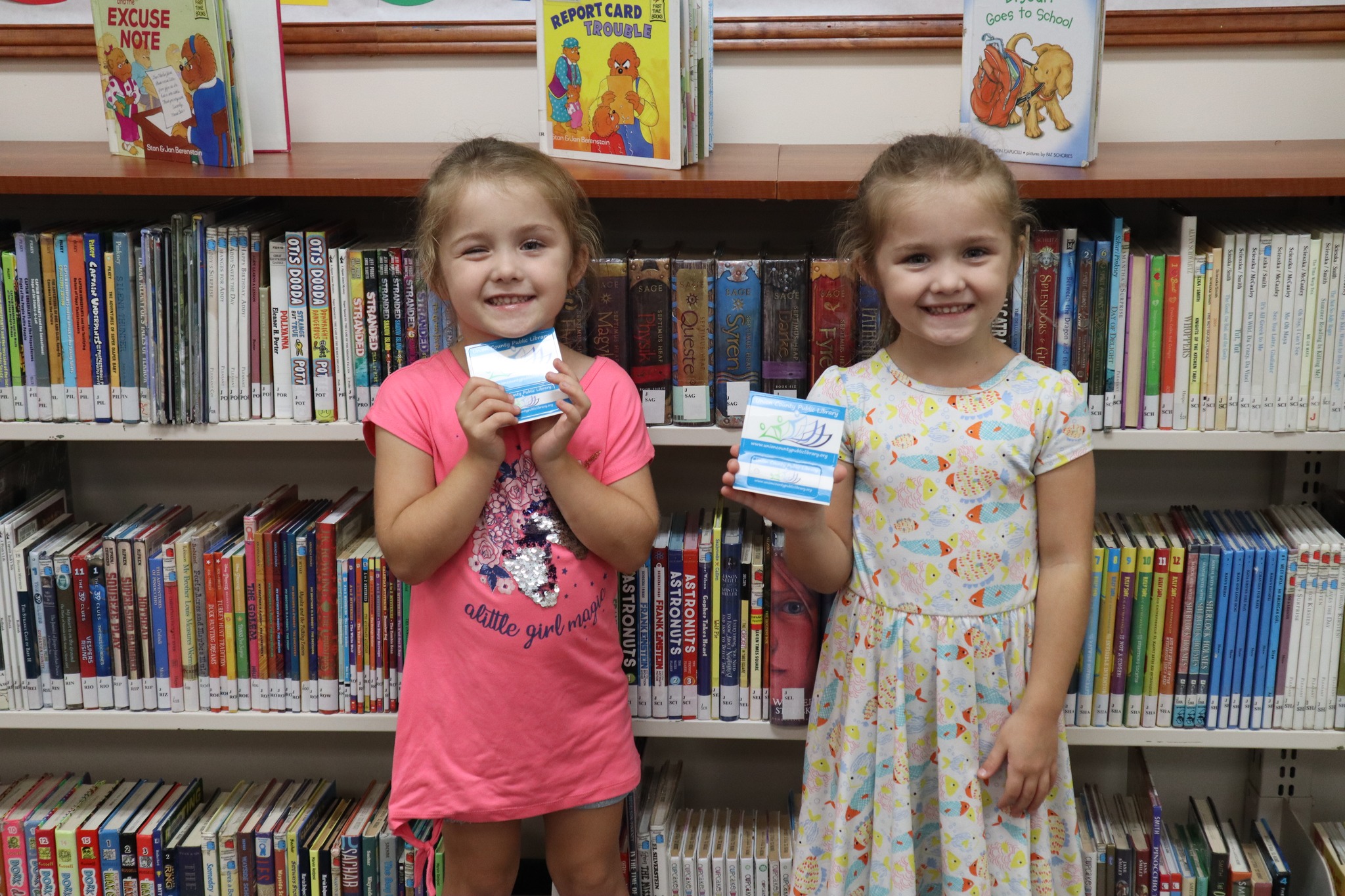 Two small girls holding new library cards